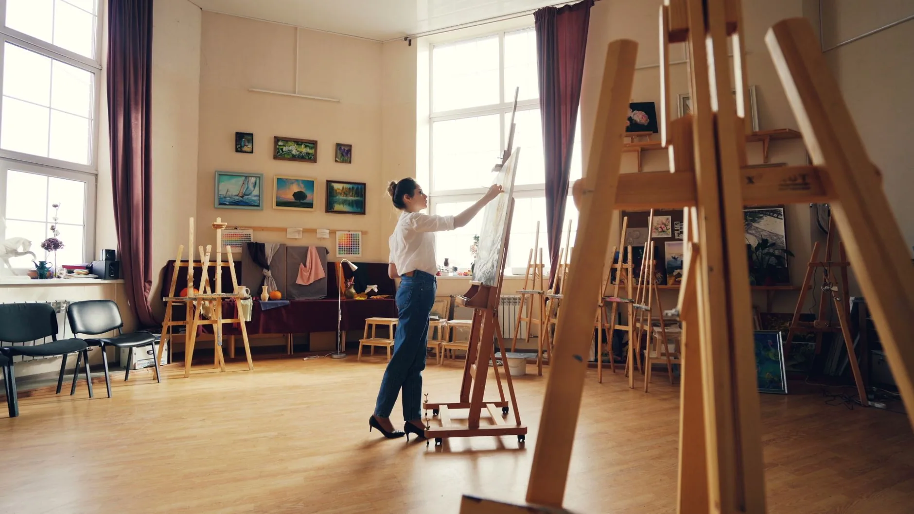 Late afternoon light illuminates a deserted art studio, showcasing creative tools and artwork. Visual arts composition.
